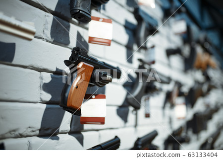 Handguns on showcase in gun shop closeup, nobody Handguns on showcase in gun shop closeup, nobody 63133404