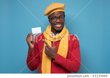 Young african man showing on white card on blue background. Young african man showing on white card on blue background. 63133989