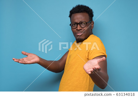 Unhappy man in glasses making arms out asking what is the problem who cares 63134018