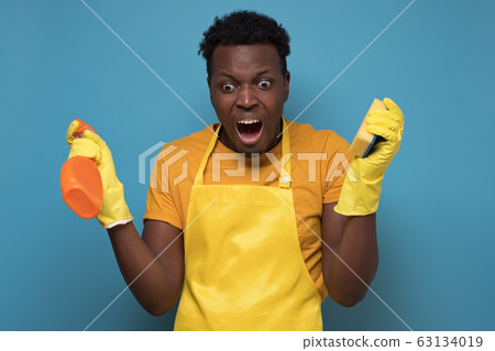 man holding sponges and washing spray being upset not wanting to do cleaning 63134019
