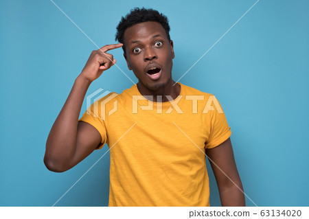 Puzzled black man in yellow shirt looking in shock and frustration at the camera 63134020