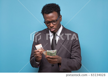 Serious african american business man counting money. Serious african american business man counting money. 63134028