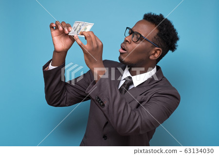 business man in suit and glasses standing, holding money checking it on fake business man in suit and glasses standing, holding money checking it on fake 63134030
