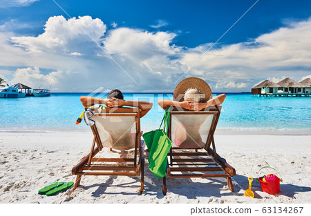 Couple in sun beds on a tropical beach 63134267