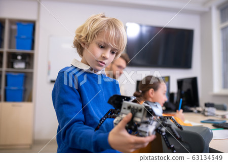 Boy holding building kit, teacher and girl in background 63134549