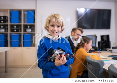 Boy holding buildable car, teacher and girl sitting at desk 63134550
