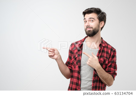 Sad gloomy european boyfriend frowning displeased pointing with finger aside. 63134704