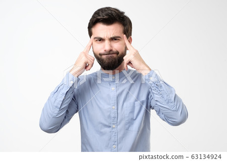 Young male keeps fingers on temples, selects best suitable solution in life Young male keeps fingers on temples, selects best suitable solution in life 63134924