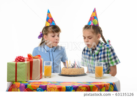 Children blow out candles on a birthday cake Children blow out candles on a birthday cake 63135126