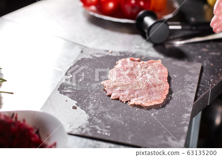 Chief chops and marinates pork. Professional chef in a kitchen of restaurant cooking. 63135200