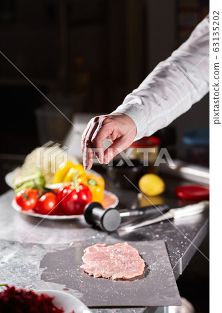 Chief chops and marinates pork. Professional chef in a kitchen of restaurant cooking. 63135202