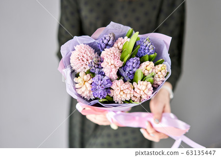 Young happy woman holding a beautiful bunch of colorful hyacinths in her hands. Present for a smiles girl. Flowers bouquet. 63135447