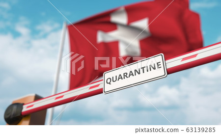 Closing boom barrier with QUARANTINE sign against the Swiss flag. Restricted border crossing or infection related isolation in Switzerland 63139285