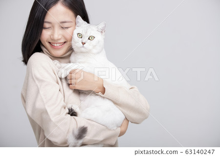 Cat cuddling woman gray background portrait 63140247