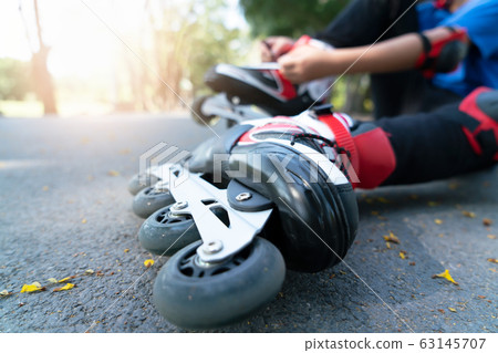 Little boy setting of laces on black roller skates 63145707