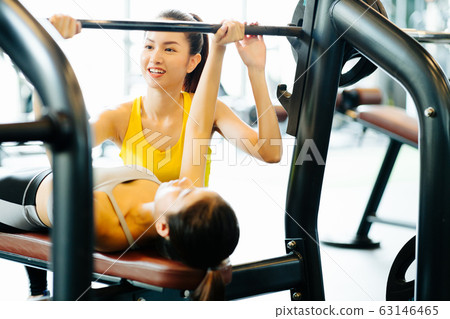 Trainer and woman doing bench press Trainer and woman doing bench press 63146465