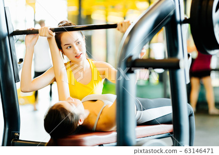 Trainer and woman doing bench press Trainer and woman doing bench press 63146471