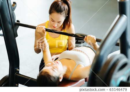 Trainer and woman doing bench press Trainer and woman doing bench press 63146479