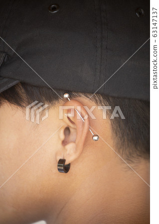 Pierced ear of young boy. 63147137