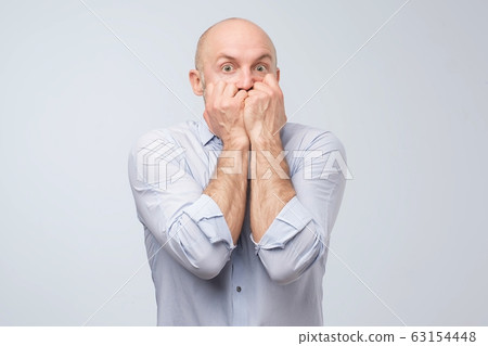 Scared mature man covering mouth. Studio shot. Male saw a ghost. 63154448