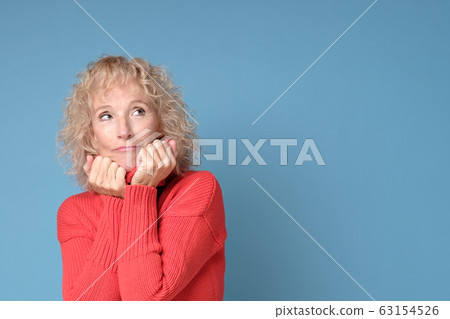 Elderly lady with a lively smile posing against a blue background 63154526