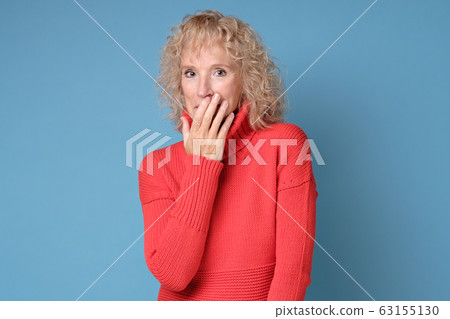 Senior woman giggles covering her mouth with hand Senior woman giggles covering her mouth with hand 63155130