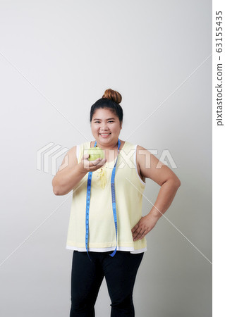 Overweight woman eating food on gray background 63155435