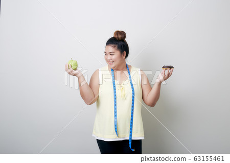 Overweight woman eating food on gray background Overweight woman eating food on gray background 63155461