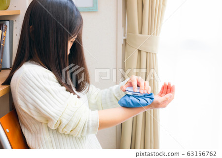 Woman chilling her wrist with ice cubes 63156762