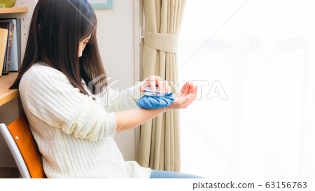 A woman cooling her wrists with an ice bag 16: 9 A woman cooling her wrists with an ice bag 16: 9 63156763