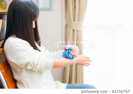 Woman chilling her wrist with ice cubes 63156767