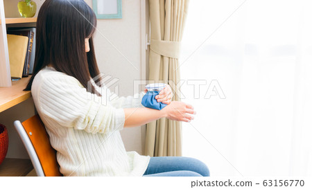 A woman cooling her wrists with an ice bag 16: 9 63156770