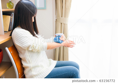 Woman chilling her wrist with ice cubes 63156772