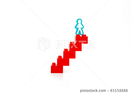 A man figurine stands on top of a red staircase. A man figurine stands on top of a red staircase. 63158886
