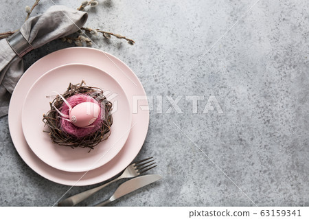 Easter table setting with pink plate decorated egg 63159341
