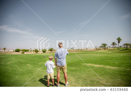 Father has fun and teaches his son to play golf on the green grass 63159488