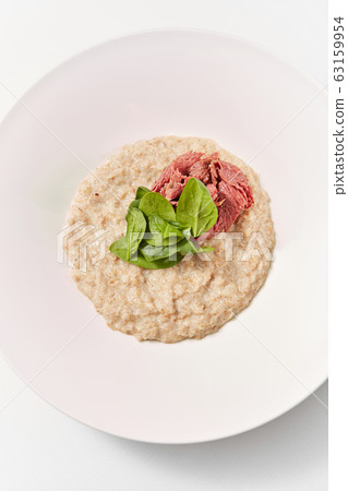 Diet food oatmeal porridge with spinach and ham in the plate. 63159954