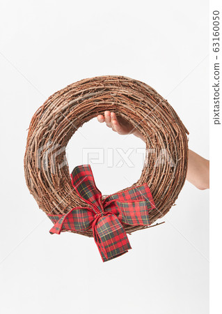 Round wreath from dry twigs with bow in a woman hand. 63160050