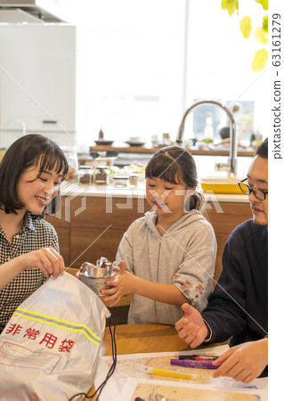 Parent and child putting luggage in emergency carry-out bag 63161279