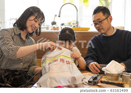 一對夫婦看著一個孩子把行李放在應急外賣袋裡 63161499