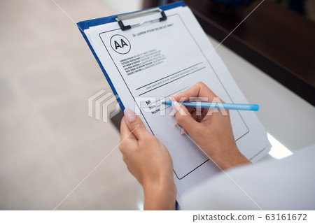 Close up of receptionist holding pen while making notes Close up of receptionist holding pen while making notes 63161672