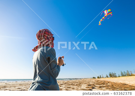 Boy launching his kite on the beach Boy launching his kite on the beach 63162378