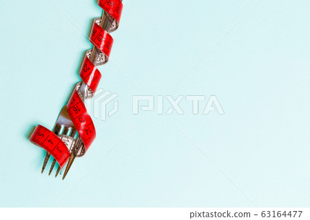 Top view of wrapped fork in tape measure on blue Top view of wrapped fork in tape measure on blue 63164477
