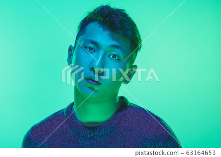 Portrait of a guy with colorful neon light on green background - cyberpunk concept Portrait of a guy with colorful neon light on green background - cyberpunk concept 63164651