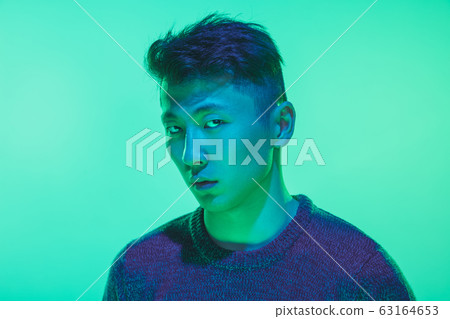 Portrait of a guy with colorful neon light on green background - cyberpunk concept 63164653