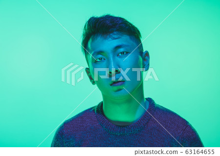 Portrait of a guy with colorful neon light on green background - cyberpunk concept Portrait of a guy with colorful neon light on green background - cyberpunk concept 63164655