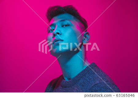 Portrait of a guy with colorful neon light on pink background - cyberpunk concept Portrait of a guy with colorful neon light on pink background - cyberpunk concept 63165046