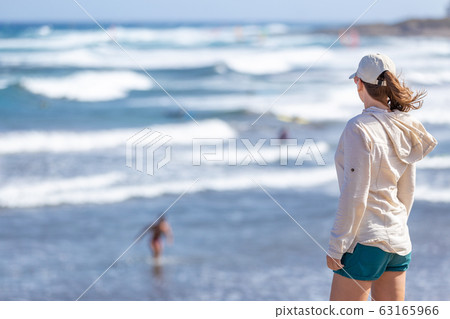 Woman looking at surfing beach El Medano, Tenerife Woman looking at surfing beach El Medano, Tenerife 63165966