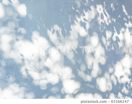 Lacy shadows from palm trees on the blue wall. Abstract background with a nice texture. Lacy shadows from palm trees on the blue wall. Abstract background with a nice texture. 63166247