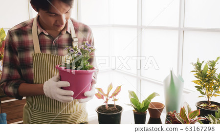 Young gardener man holding flowerpot in the room. 63167298